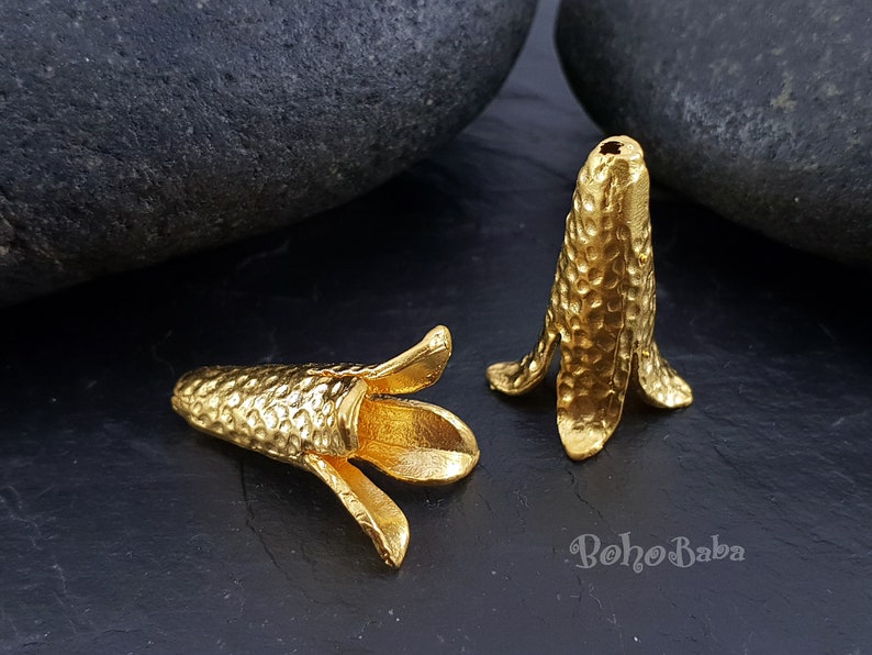 Puede incluir: Dos tapas de cuentas de metal de color dorado con textura martillada. Las tapas est&aacute;n dise&ntilde;adas para ser utilizadas como tapas finales para la elaboraci&oacute;n de joyas.
