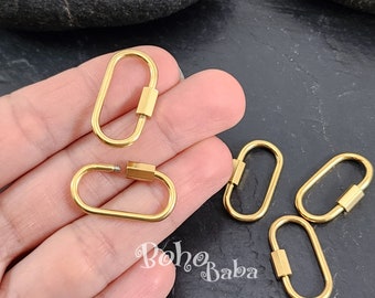 May include: Five gold-colored metal lobster clasps, also known as trigger snaps, are shown on a hand. The clasps are oval-shaped with a screw-on closure.