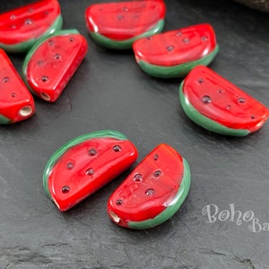 Puede incluir: Cuentas de rodajas de sandía rojas y verdes con detalles de semillas de color rojo oscuro. Estas cuentas de vidrio hechas a mano tienen forma de rodajas de sandía. Las cuentas tienen un acabado brillante.