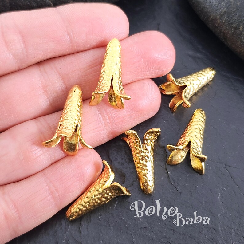 Puede incluir: Seis terminales de cord&oacute;n de metal dorado en forma de flor con una superficie texturizada.