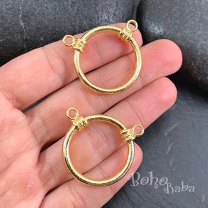 May include: Two gold-toned metal rings with a textured finish. Each ring has two jump rings attached to the top.