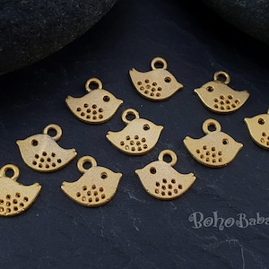 May include: A collection of ten gold-colored metal bird charms with a dotted pattern. The charms have a loop at the top for attaching to jewelry or other crafts.