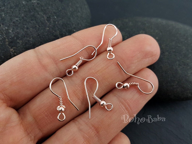 May include: Five rose gold earring hooks with a small ball at the top of each hook.