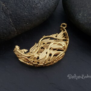 May include: Gold-toned metal pendant shaped like a leaf with intricate cut-out details. The pendant has a delicate, airy design and would be a beautiful addition to a necklace or bracelet.
