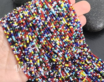 Könnte beinhalten: Eine Strähne bunter Perlen, mit einem Mix aus roten, blauen, weißen, gelben, grünen und schwarzen Perlen. Die Perlen sind klein und gleichmäßig in der Größe, wodurch ein lebendiges und strukturiertes Aussehen entsteht.