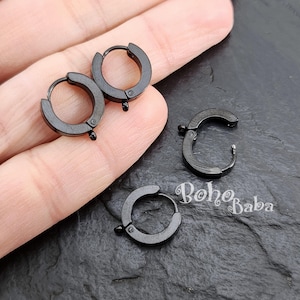 May include: Four black metal hoop earring findings with a jump ring closure. The findings are approximately 2.5 cm in diameter.