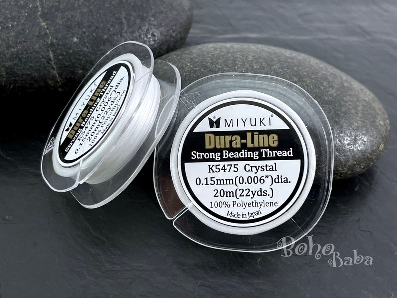 Pu&ograve; includere: Bobina bianca di filo per perline resistente Dura-Line di Miyuki. L'etichetta riporta "K5475 Crystal 0,15 mm (0,006") dia. 20 m (22 yds.) 100 % Polietilene Prodotto in Giappone"
