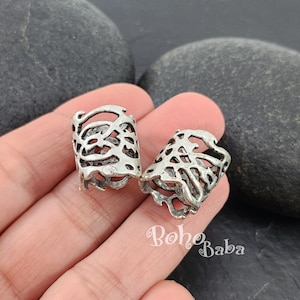 Puede incluir: Dos pasadores de pelo de metal plateado con un diseño delicado y calado. Los pasadores se muestran en una mano, con el texto "Boho Baba" visible en la esquina inferior derecha.