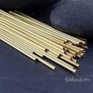 May include: A pile of gold-colored metal tubes, likely for jewelry making, on a dark gray surface. The tubes are arranged in a fan shape, with the ends of the tubes visible.
