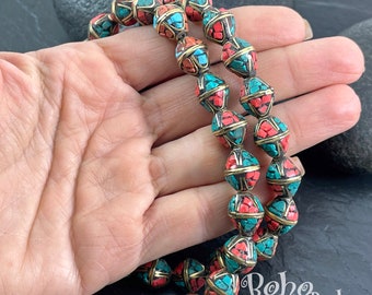 May include: A strand of beads made of brass and inlaid with turquoise and coral. The beads are faceted and have a geometric shape. The beads are strung on a cord and are ready to be used for jewelry making.