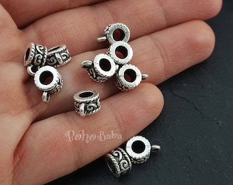 May include: Six silver metal bead caps with intricate designs. The bead caps have a hole in the center and are designed to be used for jewelry making.