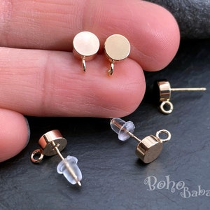 Peut inclure: Quatre fermoirs de boucles d'oreilles dorés avec un dessus rond et une boucle. Deux des fermoirs ont un axe et un bouchon en caoutchouc transparent. Les deux autres fermoirs ont une boucle sur le dessus.