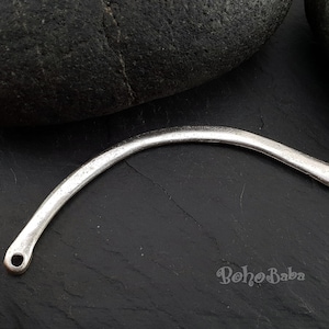May include: Silver-toned metal connector with two holes, curved into an arc shape. The connector is on a dark gray surface.