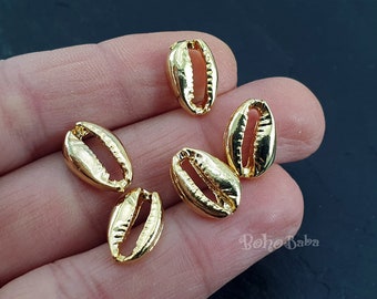 May include: Five gold-colored cowrie shell charms. The shells are smooth and have a slightly textured surface.