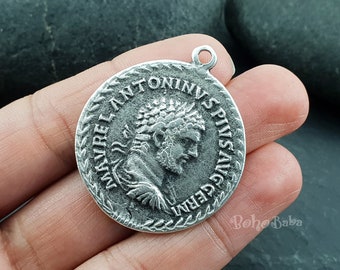 May include: Silver pendant charm with a Roman emperor's profile and inscription "IMP ANTONINVS PIVS AVG GERM".
