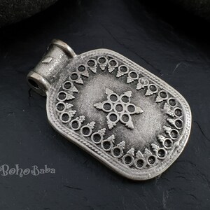 May include: Silver pendant with a star-shaped design and intricate details. The pendant has a rectangular shape with a loop at the top for attaching to a chain.