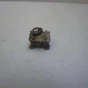 May include: Silver charm in the shape of a small house with a detailed roof and a loop at the top.