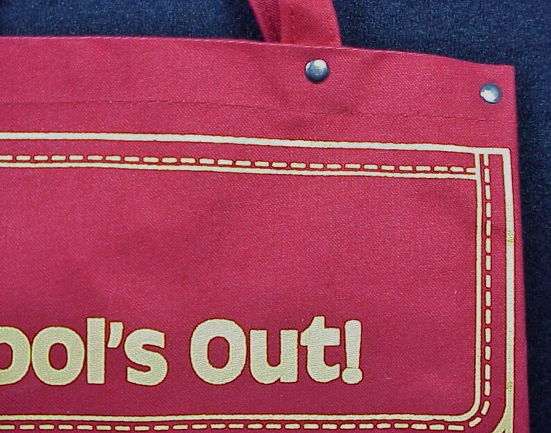 Puede incluir: Bolsa de lona roja con costuras blancas y el texto "School's Out!" en amarillo.