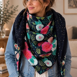 May include: A triangular scarf featuring a dark navy blue background with a vibrant floral pattern of pink, white, and teal flowers and green leaves. The scarf also includes a subtle gold speckled design throughout the fabric.