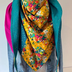 Peut inclure: Écharpe colorée avec un motif floral jaune, rose et bleu. L'écharpe est superposée avec des tissus turquoise et roses, et est drapée sur une veste en jean. Le design de l'écharpe est unique et ajoute une touche de couleur à n'importe quelle tenue.