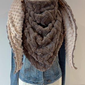 May include: A soft, grey and beige bunny ear scarf. The scarf is made of a textured fabric and has long, floppy ears. The scarf is designed to be worn around the neck and head, providing warmth and a playful look. The measurements are in centimeters.