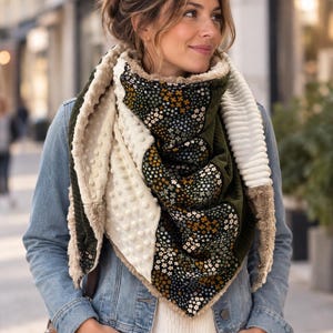 Puede incluir: Una bufanda triangular con un diseño de patchwork que combina pana verde oscuro, tela minky color crema con textura de puntos en relieve y un panel de tela negra con un pequeño estampado floral blanco y amarillo, con borde de piel sintética beige.