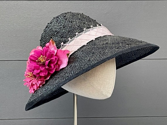 Black knotted straw hat with layered ribbon and veiling band, silk zinnias, and vintage velvet leaves