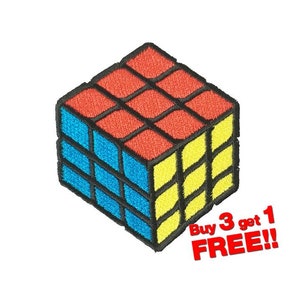 Peut inclure: Un patch brodé à repasser représentant un Rubik's Cube avec des carrés rouges, bleus et jaunes. Le patch a des contours noirs et est en perspective 3D. Le texte "Buy 3 get 1 FREE!!" est situé sous le patch.