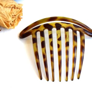 May include: A brown and black tortoiseshell hair comb with a curved top and seven teeth.