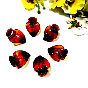 May include: Six brown heart-shaped hair clips. The clips are made of plastic and have a shiny finish.