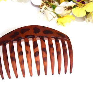 May include: A brown and black tortoiseshell comb with a leopard print pattern.