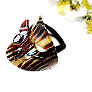 May include: A black and brown striped hair clip with a red and white butterfly design.