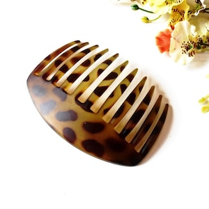 Könnte beinhalten: Ein brauner und beiger Haarkamm mit Leopardenmuster. Der Kamm hat sieben Zähne.