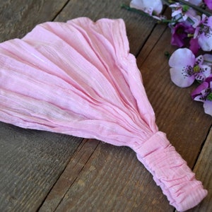 May include: A pink fabric headband with a gathered end. The headband is made of a soft, lightweight material and is perfect for adding a touch of colour to any outfit.