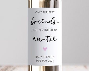 May include: A white wine bottle with a label that reads "Only the best friends get promoted to auntie". A pink heart is below the text. The label also includes the text "Baby Clayton Due May 2024".