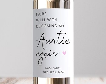 May include: A white wine bottle with a label that says "Pairs well with becoming an Auntie again" with a pink heart. The label also says "Baby Smith Due April 2024".