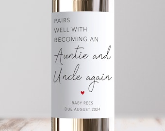 May include: White wine bottle with a label that says "Pairs well with becoming an Auntie and Uncle again" with a red heart and "Baby Rees Due August 2024".