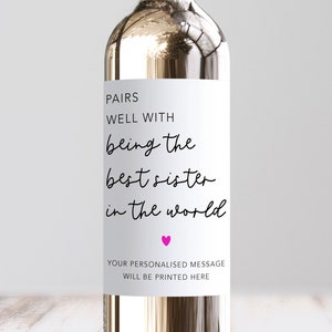May include: White wine bottle with a label that reads "Pairs well with being the best sister in the world". A pink heart is below the text. The label also says "Your personalised message will be printed here".