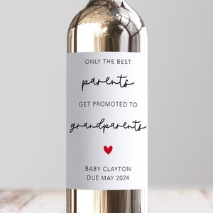 May include: White wine bottle with a label that reads "Only the best parents get promoted to grandparents" with a red heart and the text "Baby Clayton Due May 2024".