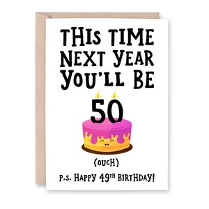 May include: A white card with black text that reads "This time next year you'll be 50 (ouch)" and "P.S. Happy 49th Birthday!"  A pink and yellow cake with a smiling face and lit candles is illustrated above the text.