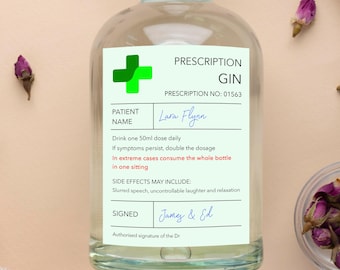 Puede incluir: Una botella de vidrio transparente con una cruz verde y el texto "Prescription Gin" en una etiqueta blanca. La etiqueta también incluye el texto "Prescription No: 01563", "Patient Name: Lara Flynn", "Drink one 50ml dose daily", "If symptoms persist, double the dosage", "In extreme cases consume the whole bottle in one sitting", "Side Effects May Include: Slurred speech, uncontrollable laughter and relaxation", "Signed: James & Ed", y "Authorised signature of the Dr."