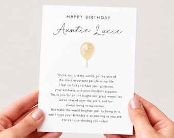 May include: A white rectangular birthday greeting card featuring the text "HAPPY BIRTHDAY" in black capital letters, followed by "Auntie Lucie" in a script font, a single gold glitter balloon illustration, and a heartfelt message in black text.