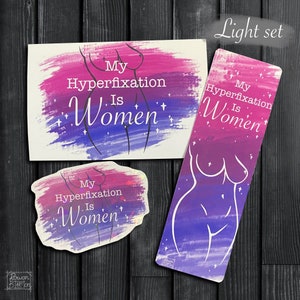 May include: A set of three items featuring a stylised female figure with the text "My Hyperfixation Is Women" in a pink and purple watercolour style. The set includes a bookmark, a sticker, and a card.