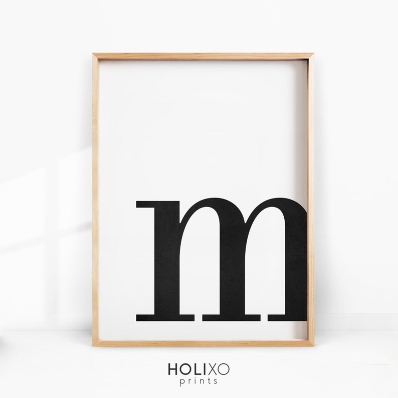 May include: Black and white printable wall art featuring the letter "m" in a bold, sans-serif font. The letter is centered on a white background and framed in a light wood frame.