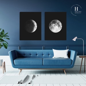 May include: Two black and white prints of the moon in different phases. The prints are framed and hanging on a dark blue wall above a blue sofa.