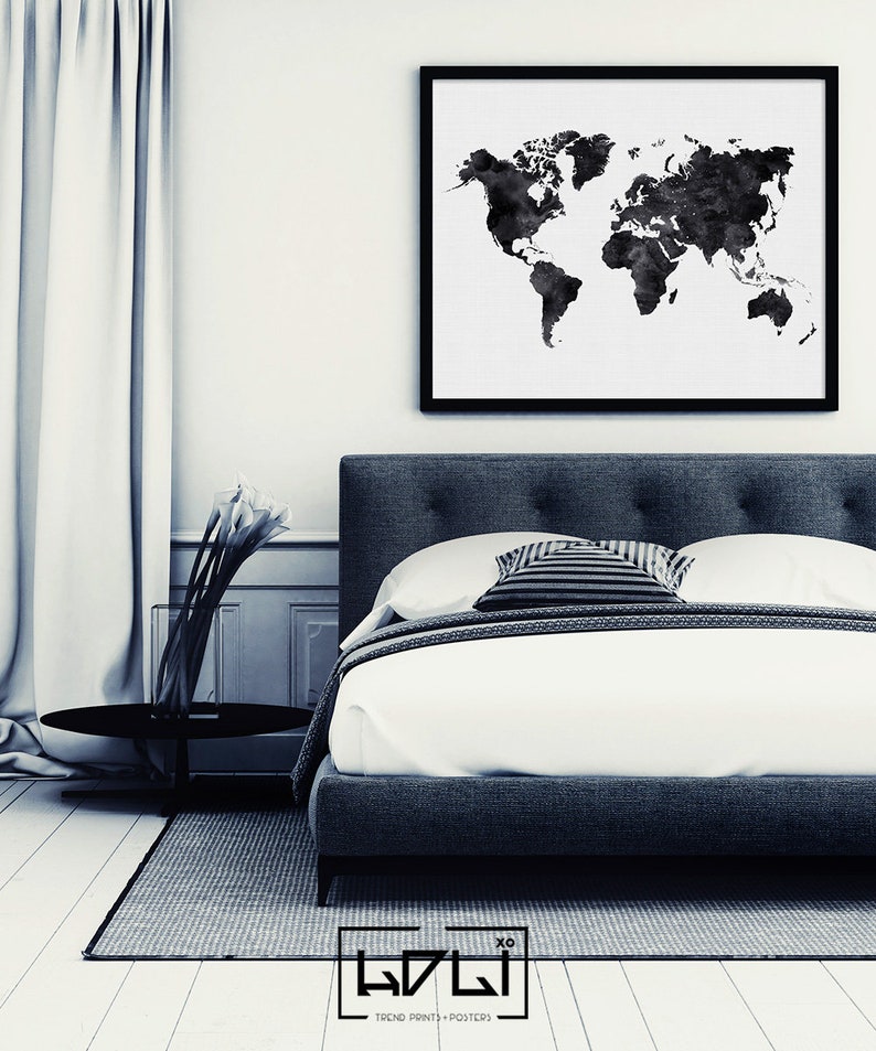 Puede incluir: Una impresi&oacute;n de mapa del mundo en acuarela en blanco y negro en un marco negro que cuelga sobre una cama tapizada en gris con ropa de cama blanca y una almohada a rayas en blanco y negro.