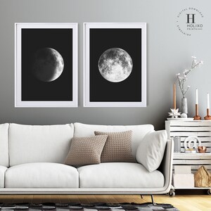 May include: Two black and white framed prints of the moon in different phases. The prints are hanging on a gray wall above a white couch with two brown throw pillows.