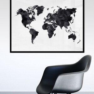 Puede incluir: Una impresi&oacute;n de mapa del mundo en acuarela en blanco y negro en un marco negro que cuelga de una pared blanca sobre una silla negra.