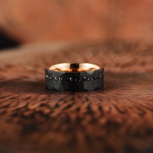 Meteorite mens wedding band crafted in meteorite hammered black tungsten and rose tungsten with a flat profile and a comfort fit interior. Rings By Pristine