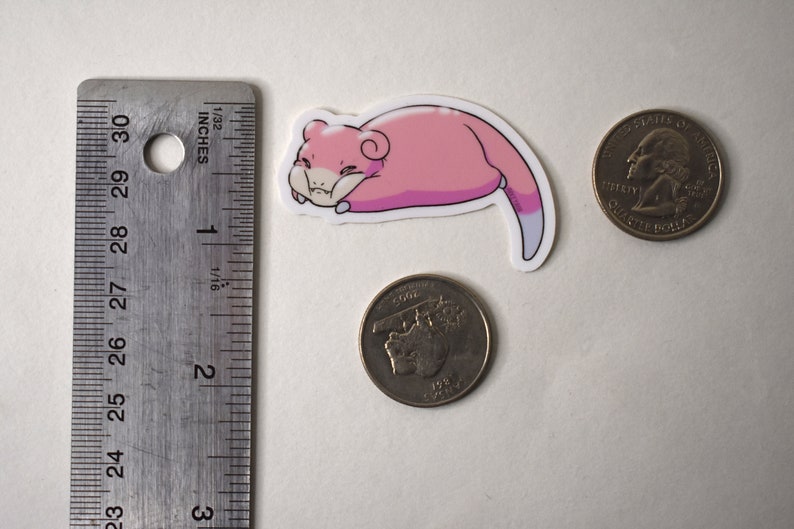 Puede incluir: Una pegatina de dibujos animados rosa y blanca de un gato durmiendo enroscado. La pegatina es aproximadamente del tama&ntilde;o de una moneda de euro.